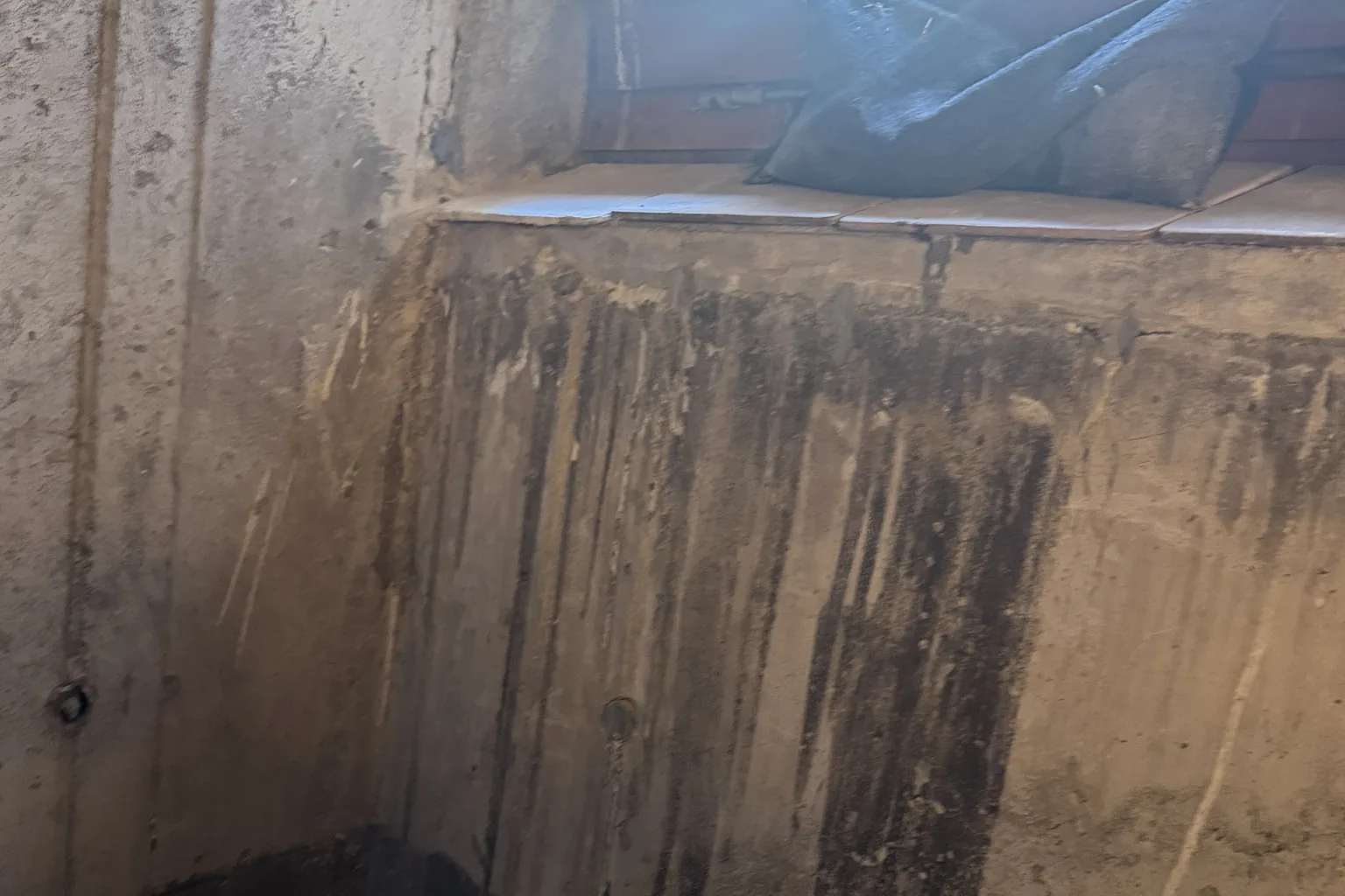 Feuchtefahnen und Sinterausblühungen an einer Kellerwand unter dem Kellerfenster