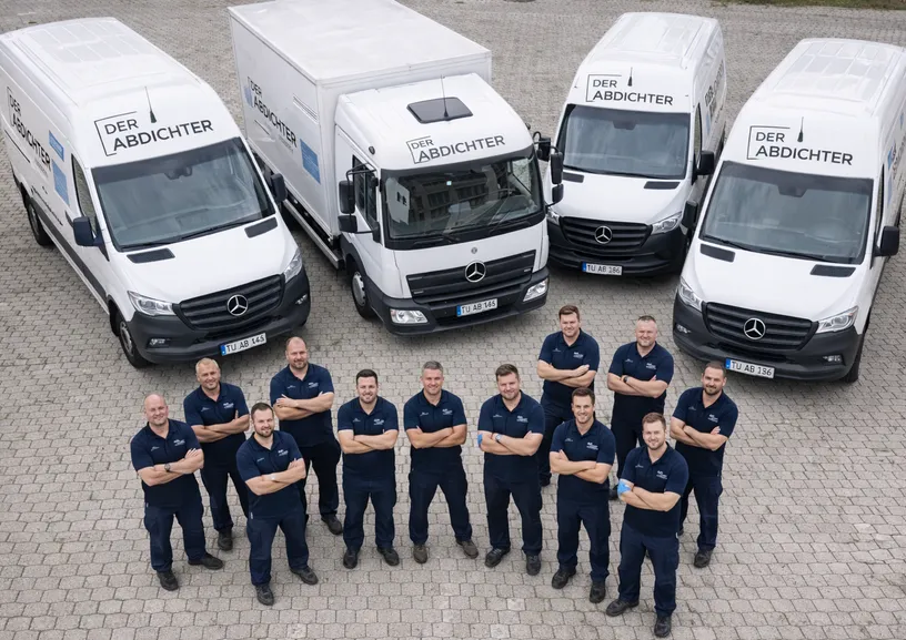 Das Team von Der Abdichter vor der Fahrzeugflotte